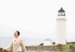 Person standing in front of a lighthouse on a foggy day