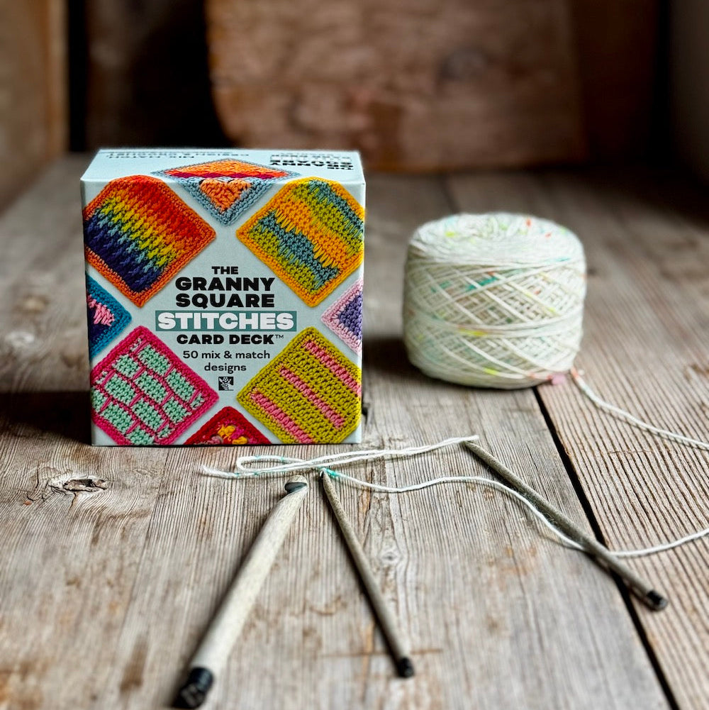 Stitches card deck and needles on a wooden surface