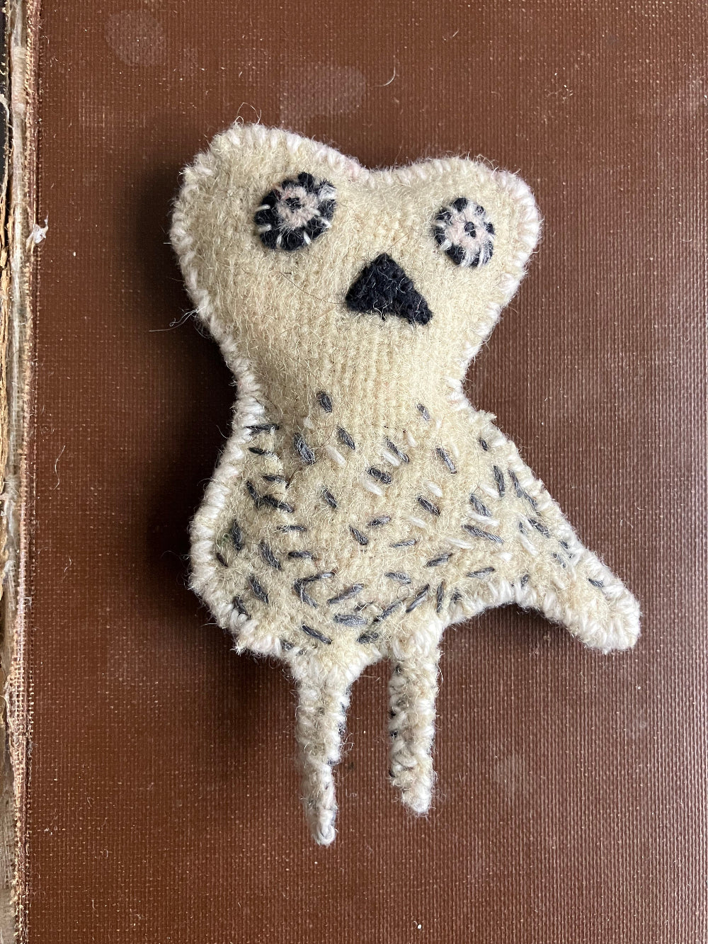 Textured stitched owl object on a brown background
