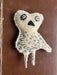 Textured stitched owl object on a brown background