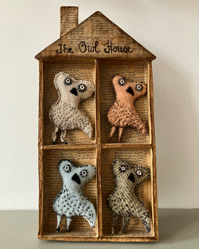 Wooden box with four knitted owl figures inside, labeled 'The Owl House'.