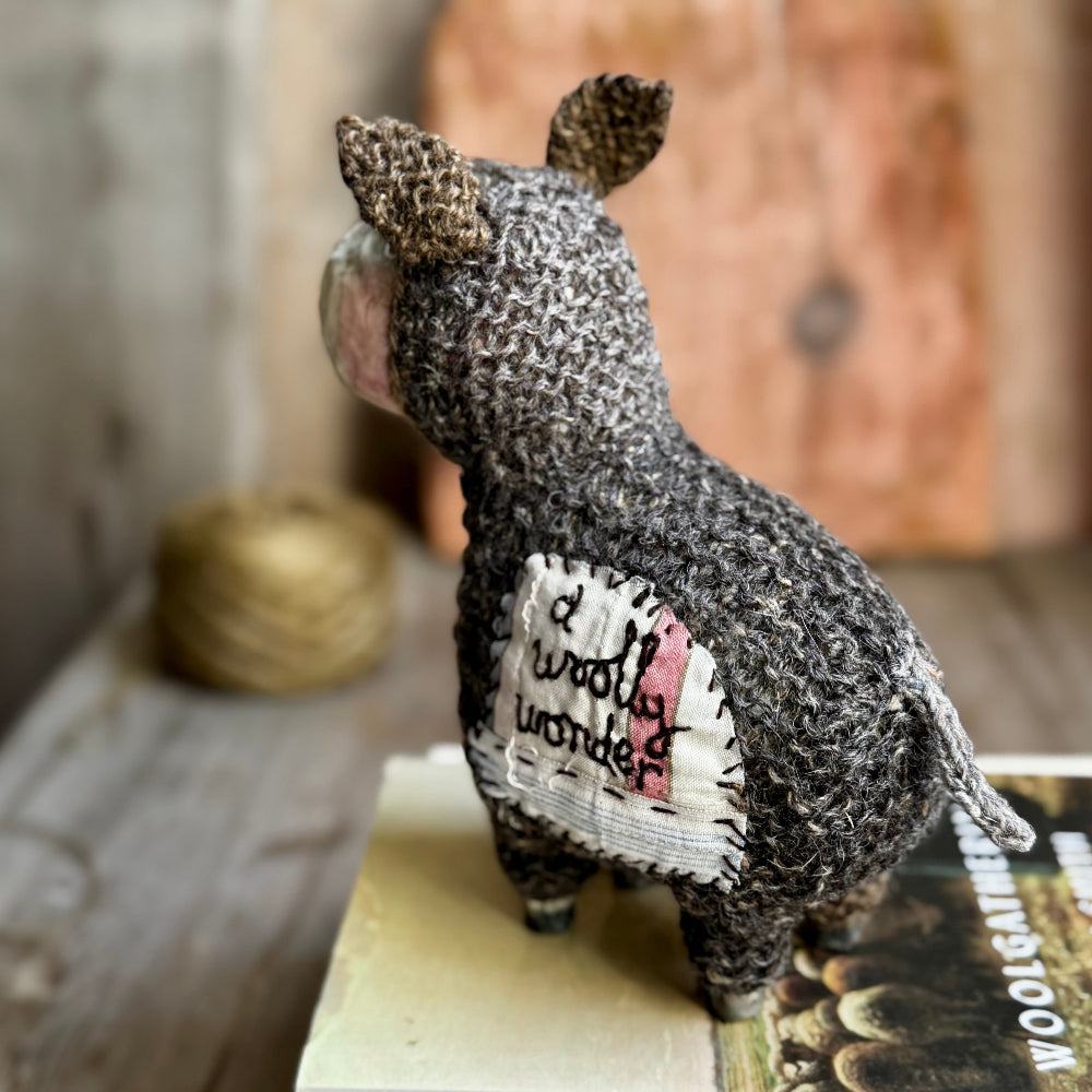 Textile art sheep figurine on a book with a blurred background