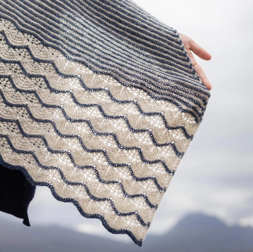 Person holding a patterned fabric against a cloudy sky