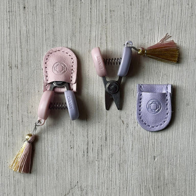 Set of mini snip tools with pink and purple handles on a textured surface