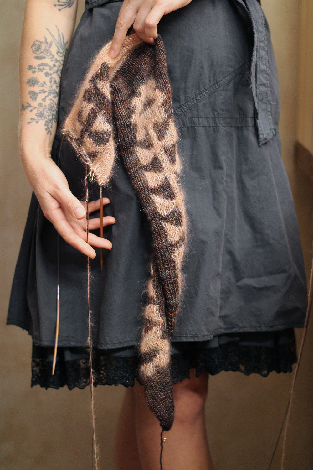 Person holding a knitted scarf with floral pattern against a neutral background