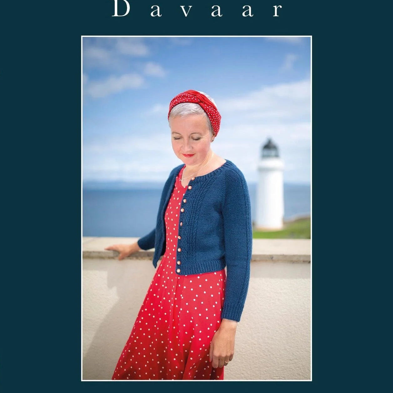 Woman in a blue cardigan and red dress standing in front of a lighthouse with 'Davaar' branding.