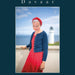 Woman in a blue cardigan and red dress standing in front of a lighthouse with 'Davaar' branding.