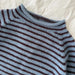 Close-up of a blue and brown striped sweater on a textured white background