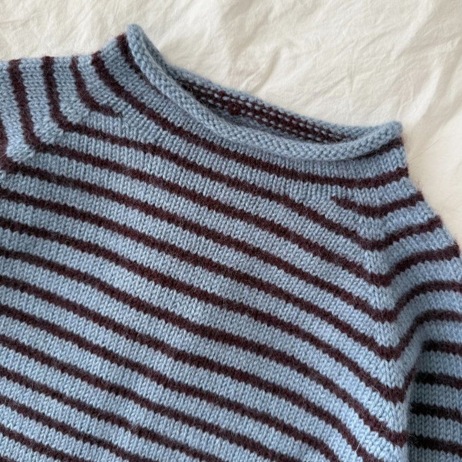 Close-up of a blue and brown striped sweater on a textured white background