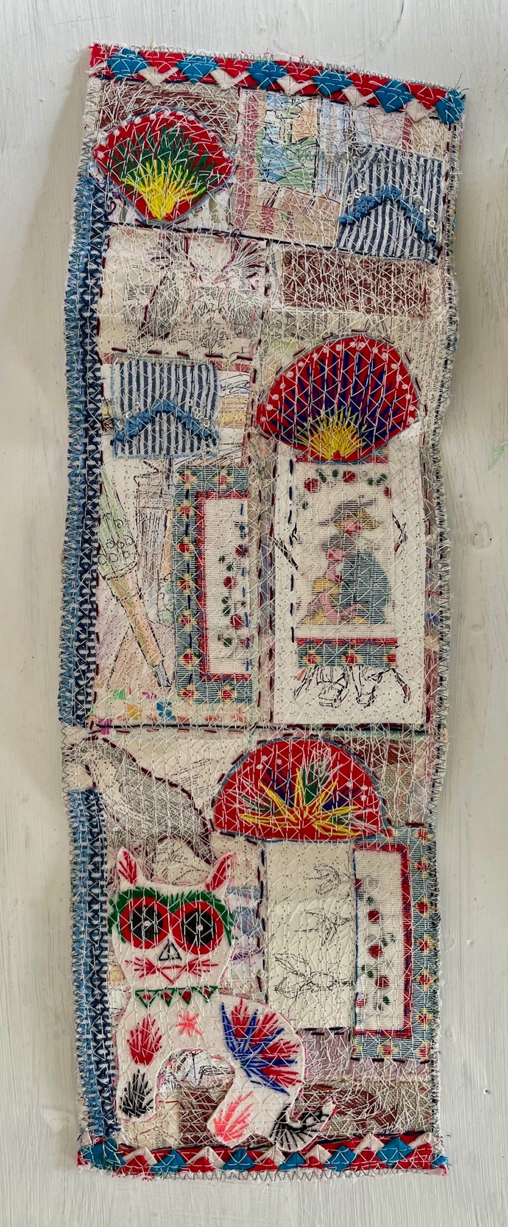Textile art piece with colorful patterns and designs on a white background