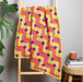 Colorful crocheted blanket draped over a wooden ladder against a neutral wall.