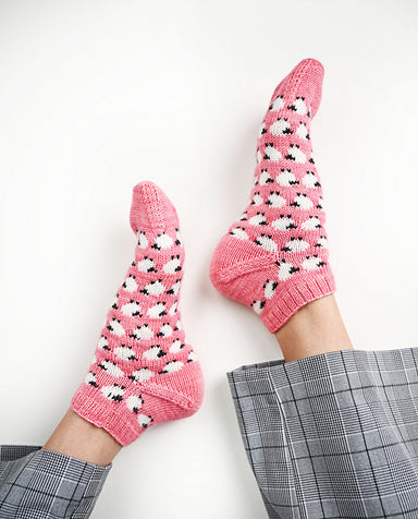 Pink socks with black and white patterns worn by a person on a white background