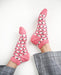 Pink socks with black and white patterns worn by a person on a white background